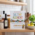 Salt, Fat, Acid, Heat on an open kitchen shelf with pantry jars