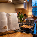 Salt, Fat, Acid, Heat open on a cookbook stand beside a cast-iron skillet